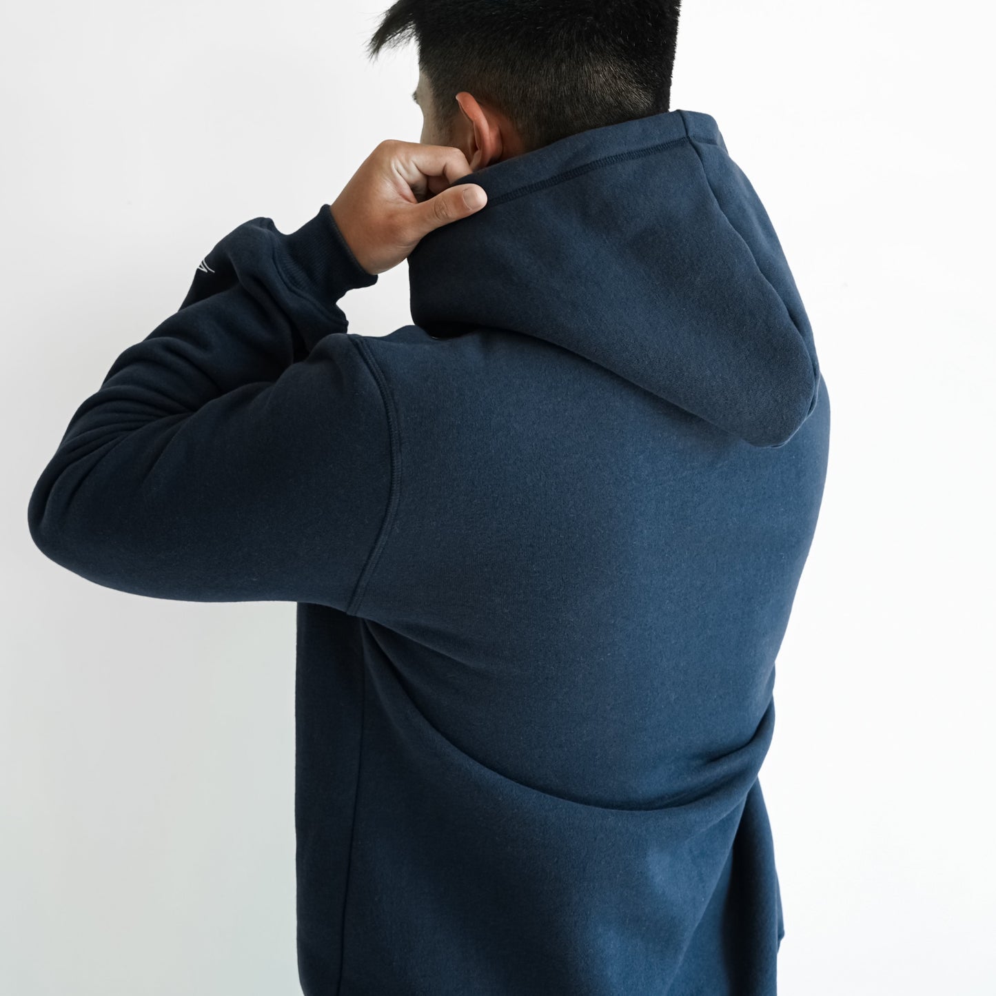 man in navy blue hoodie holding the hood