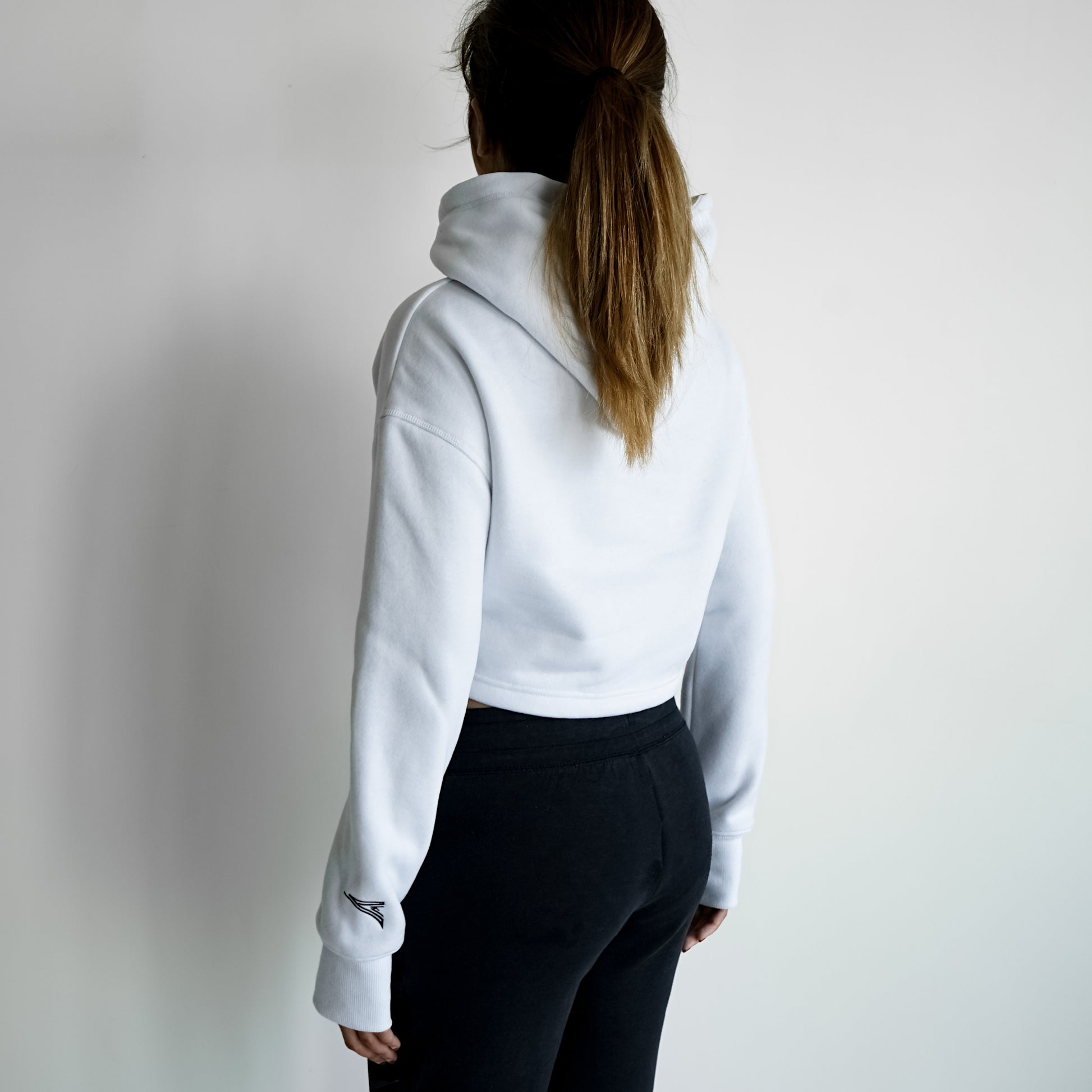 back of a woman in white cropped hoodie