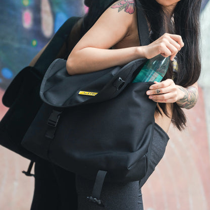 woman putting a water bottle in a black crossbody bag
