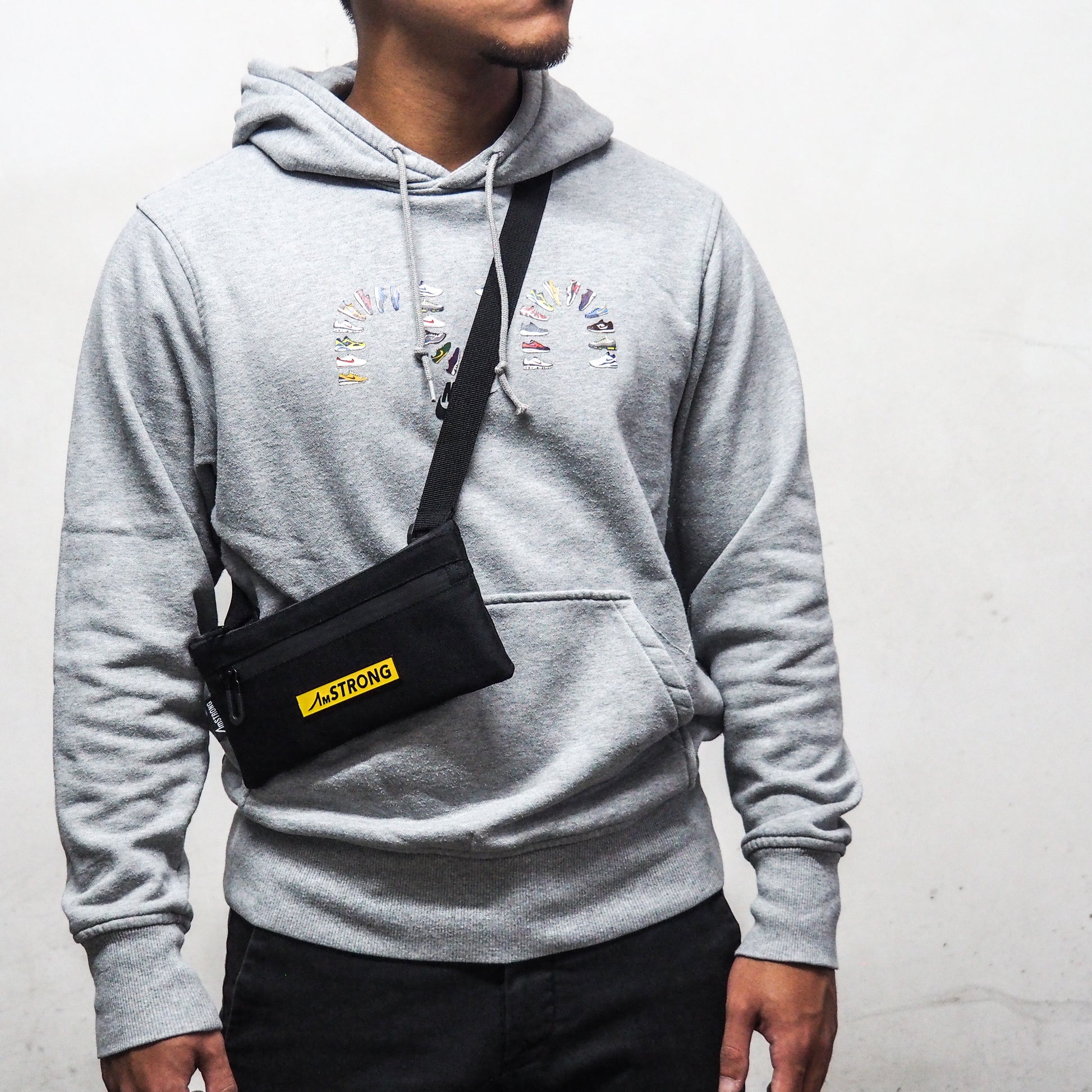  man in grey hoodie carrying a small crossbody bag