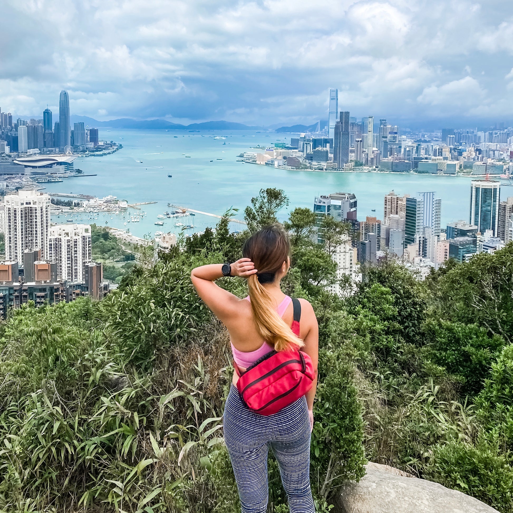woman carrying a red belt bag with the view of Victoria harbour